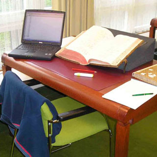 Forschertisch mit historischer Quelle und modernem Laptop